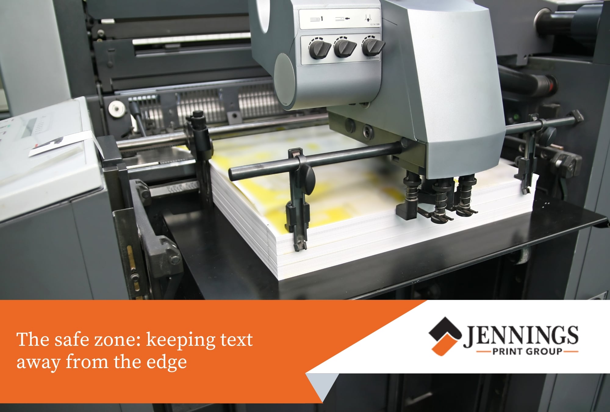 An industrial printing press feeding a stack of white paper with bleed format